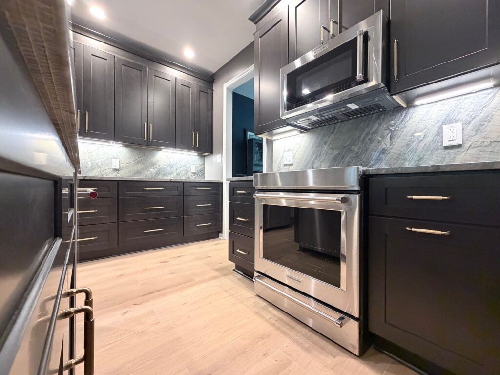Newly remodeled kitchen with dark shaker cabinets, gray Moreno quartzite countertops, a large island, stainless steel appliances, and modern pendant lighting.